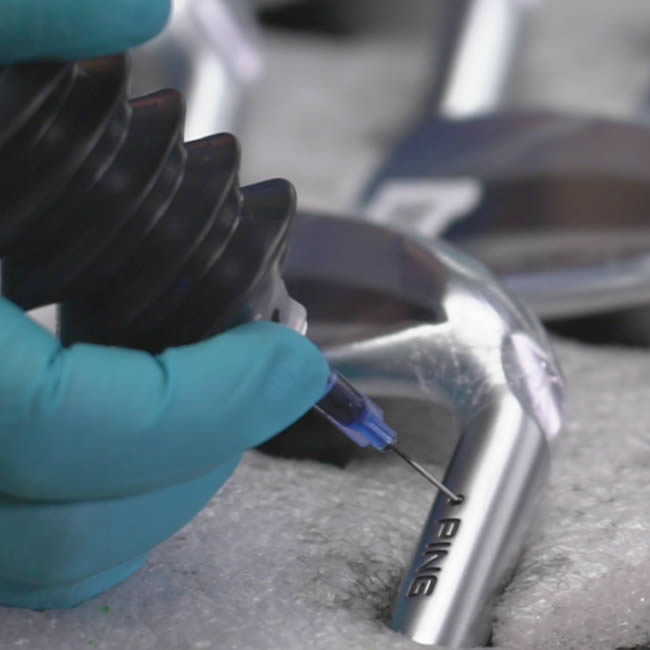 A club assembly tech paint-filling the color code on a PING iron